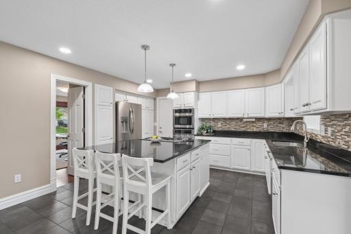 This kitchen features stainless steel appliances, double ovens, and a gas cooktop. A center island with seating and ample cabinet storage provide practical space for daily use.