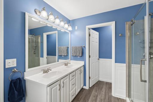 This functional primary bathroom features dual sinks and a separate toilet room with a built-in storage cabinet for added convenience.