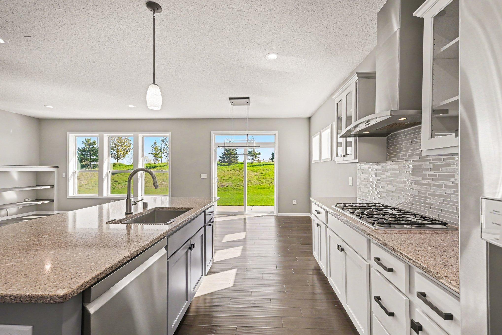Large sink, gas cooktop, glass cabinet doors, and lots of natural light
