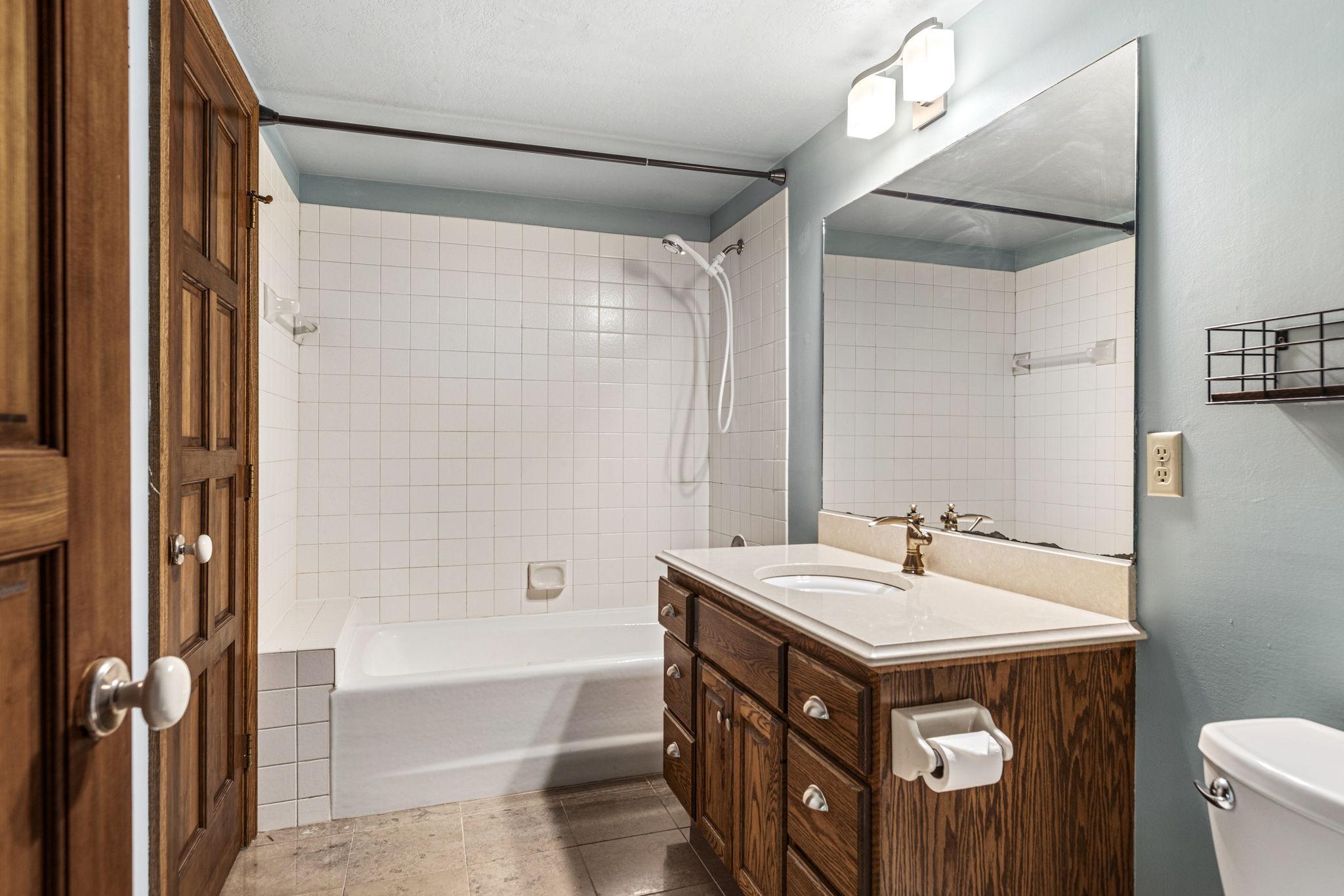 Full bathroom in lower level with tile flooring and quartz counter.