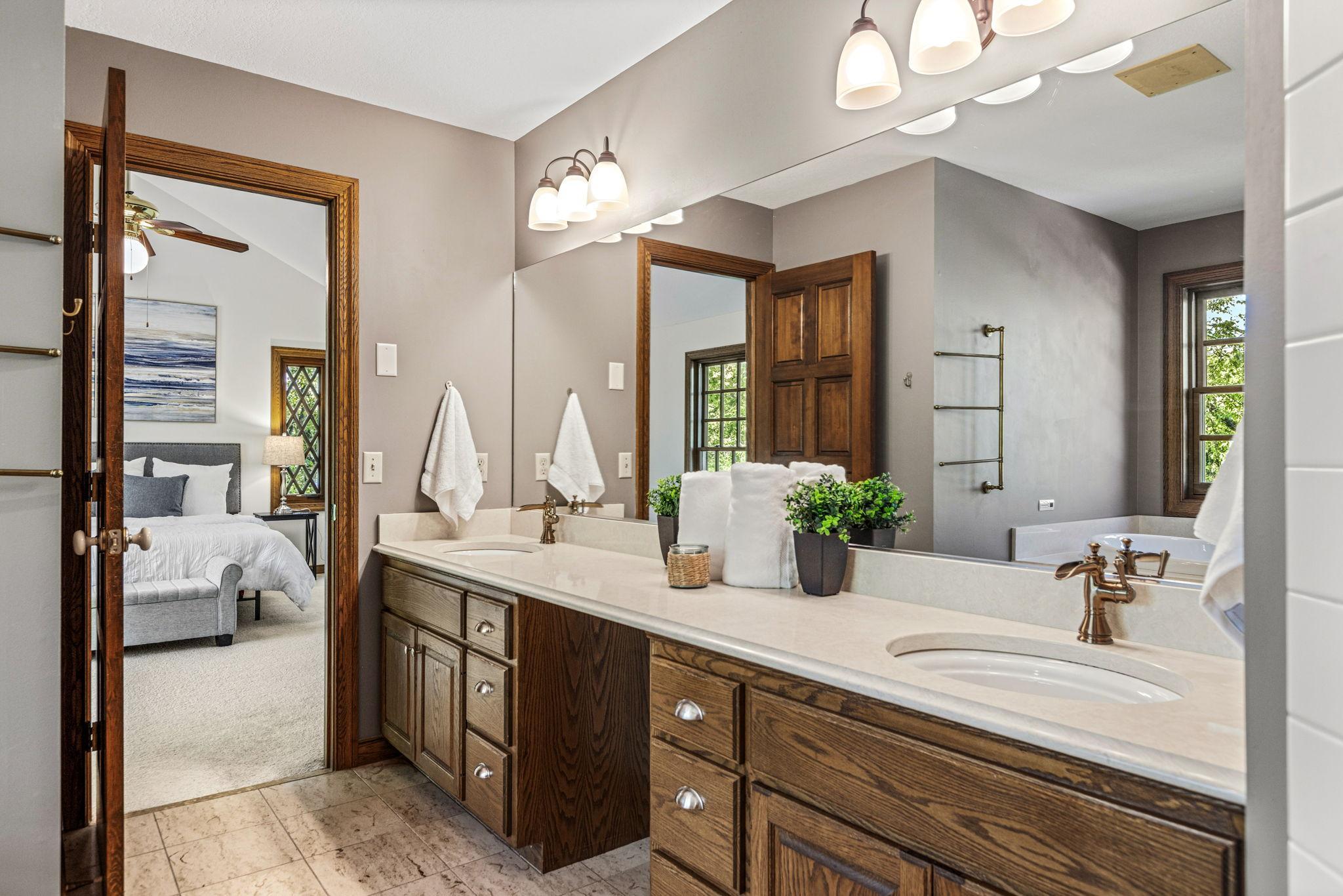 Primary full bath featuring dual sinks with quartz counter and tile flooring.