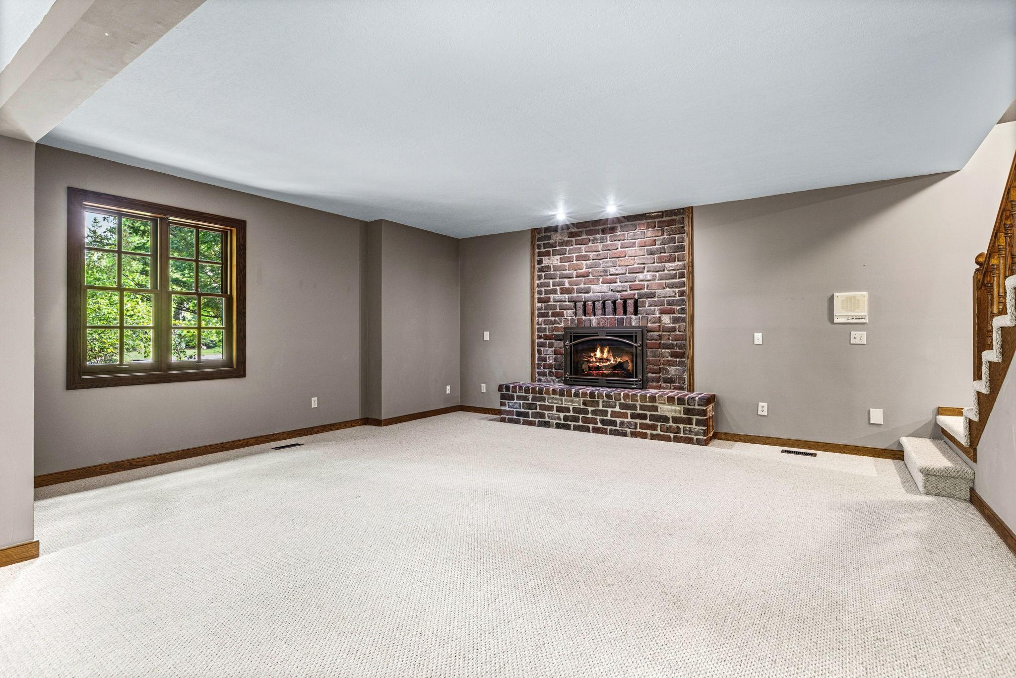 Spacious lower-level family room with cozy brick gas fireplace and endless possibilities for entertaining, movie nights or game-day gatherings.
