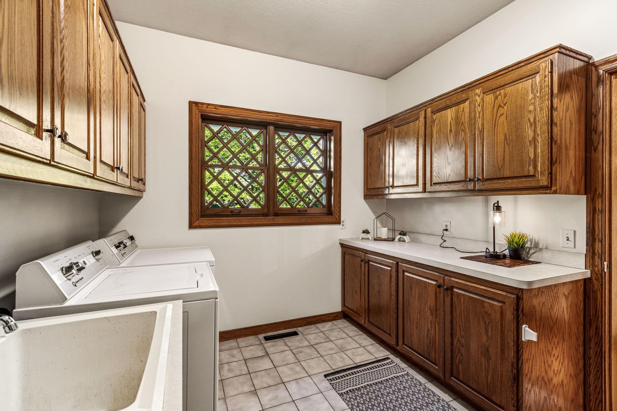 Spacious main-floor laundry room with abundant cabinetry, countertop workspace and utility sink. There is also a walk-in pantry for additional storage needs.