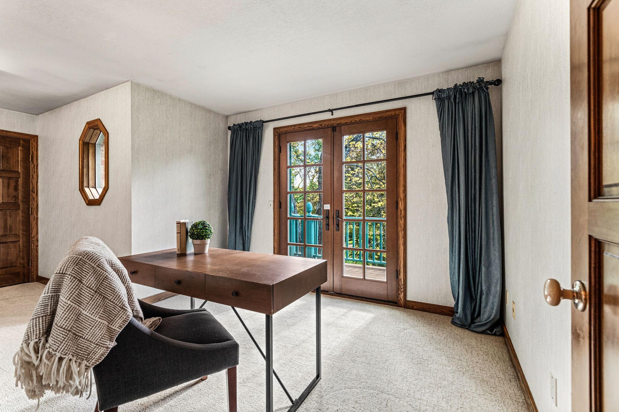 4th bedroom on upper level with French doors leading to a private balcony, This room would also be a perfect home office, reading room or creative studio with peaceful treetop views.