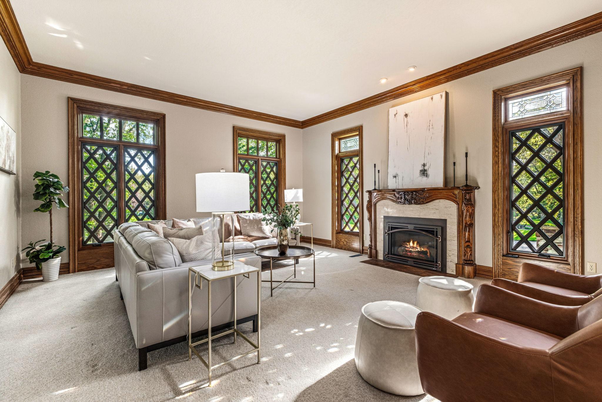 Elegant formal living room filled with natural light, featuring stunning lattice window detail, rich crown molding and a beautifully detailed fireplace mantel.