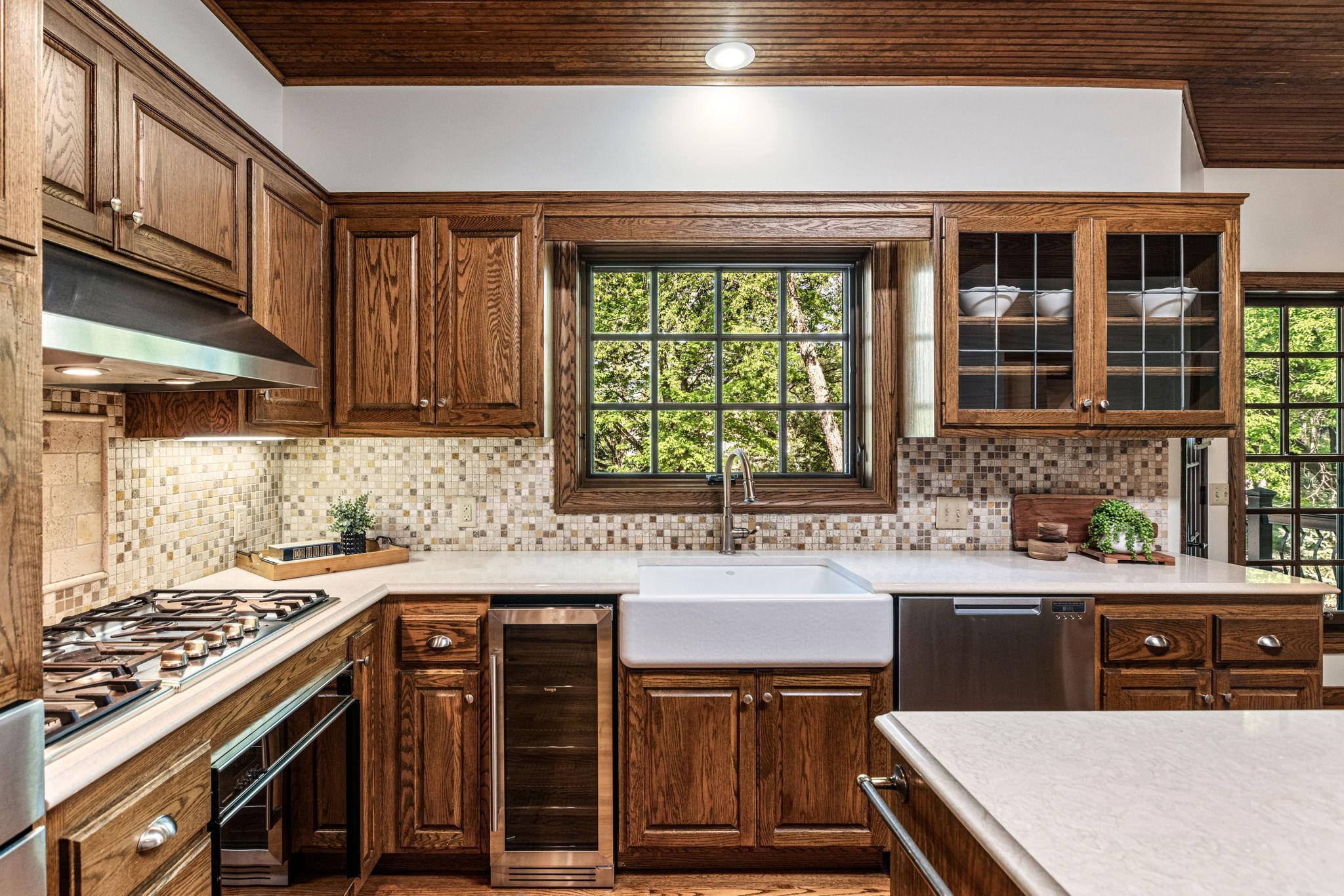 The kitchen is beautifully appointed with a gas range, farmhouse sink, quartz countertops and beverage frig.