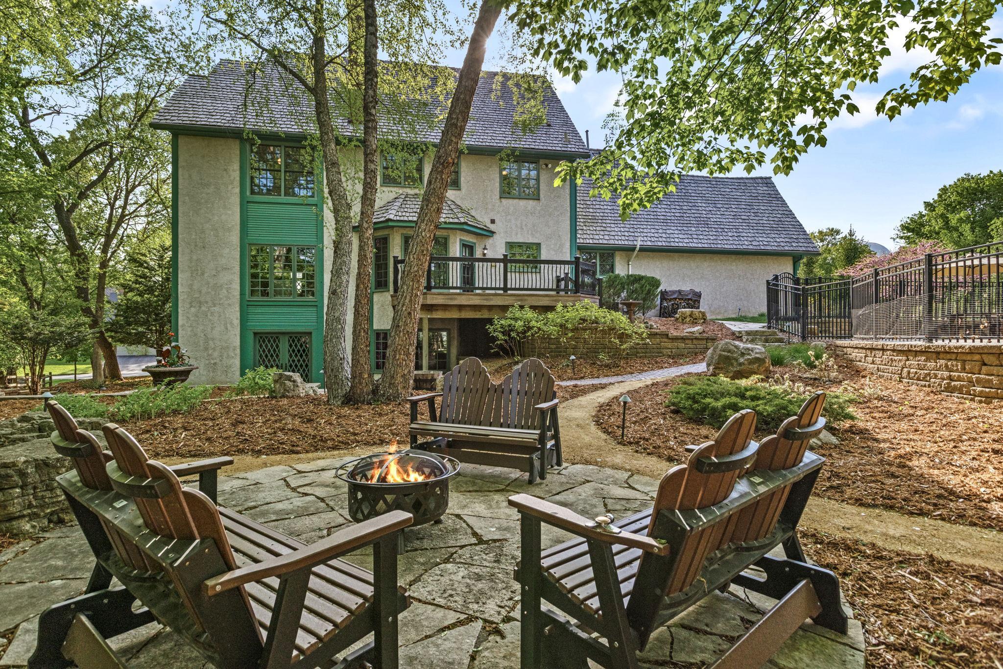 Serene backyard retreat with a flagstone patio, fire pit gathering area and mature trees creating a private, park-like setting. Multiple outdoor living spaces and thoughtfully landscaped grounds make this the perfect place to relax or entertain.
