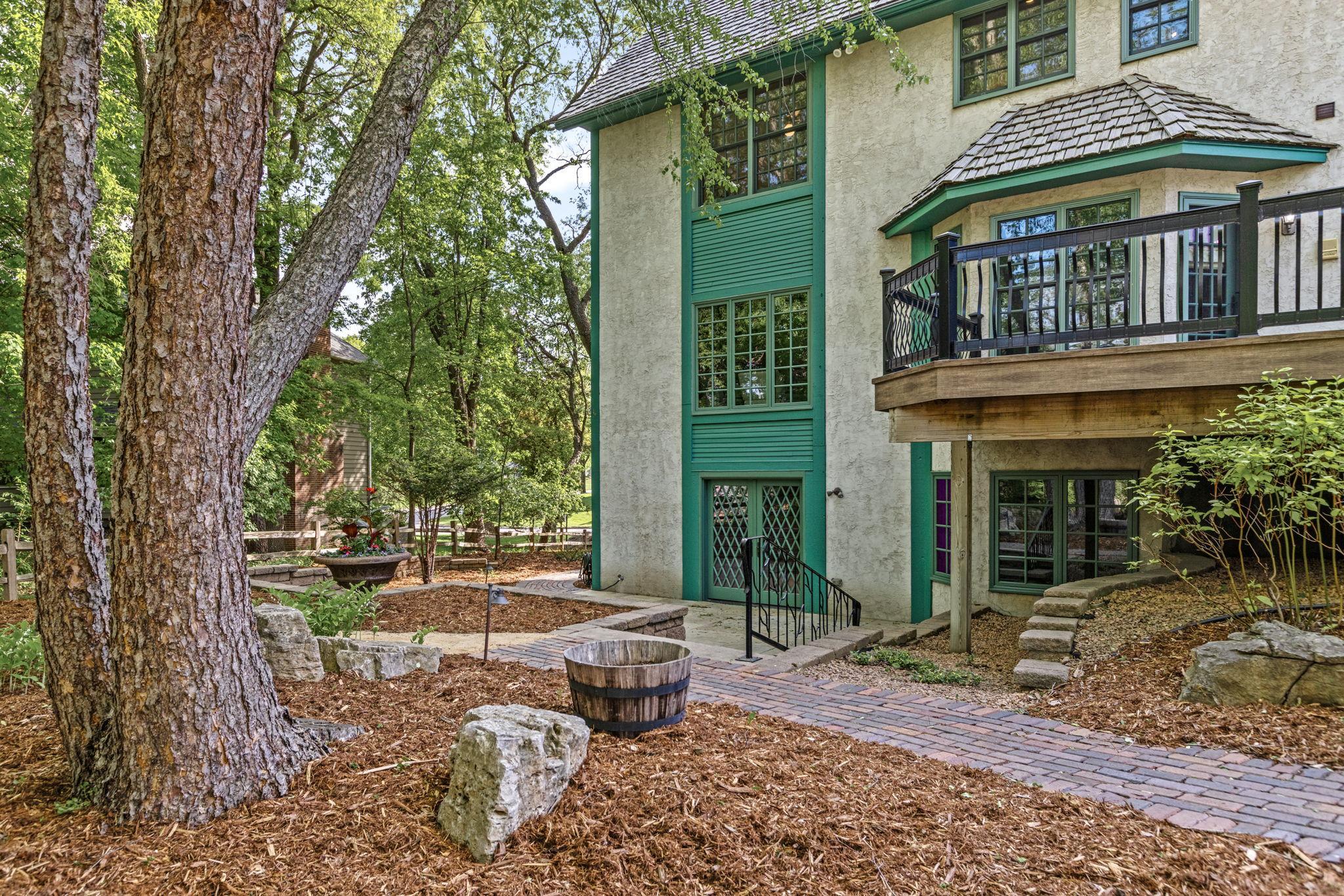 Beautifully landscaped backyard with mature trees and winding brick pathways. Fun fact: these bricks were repurposed from a downtown St. Paul historic restoration!