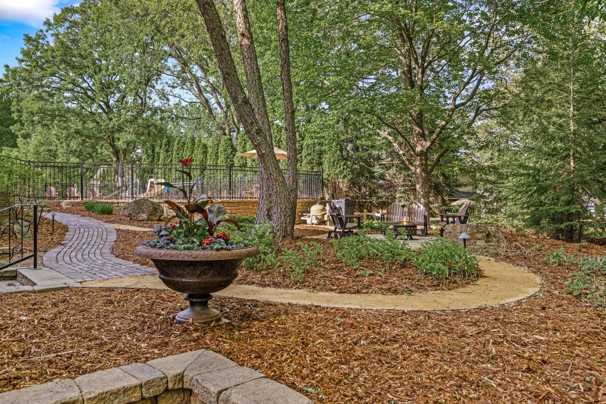 This enchanting backyard oasis was professionally designed by Minnesota Landscape between 2016–2024 and thoughtfully enhanced with retaining walls, extensive hardscaping, landscape lighting, natural boulder accents and wiring for a future hot tub!