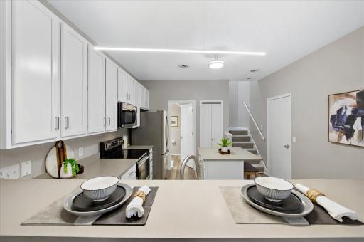 The updated kitchen shines with quartz countertops, stainless steel appliances, and abundant cabinetry, while the breakfast bar adds extra seating and everyday convenience.