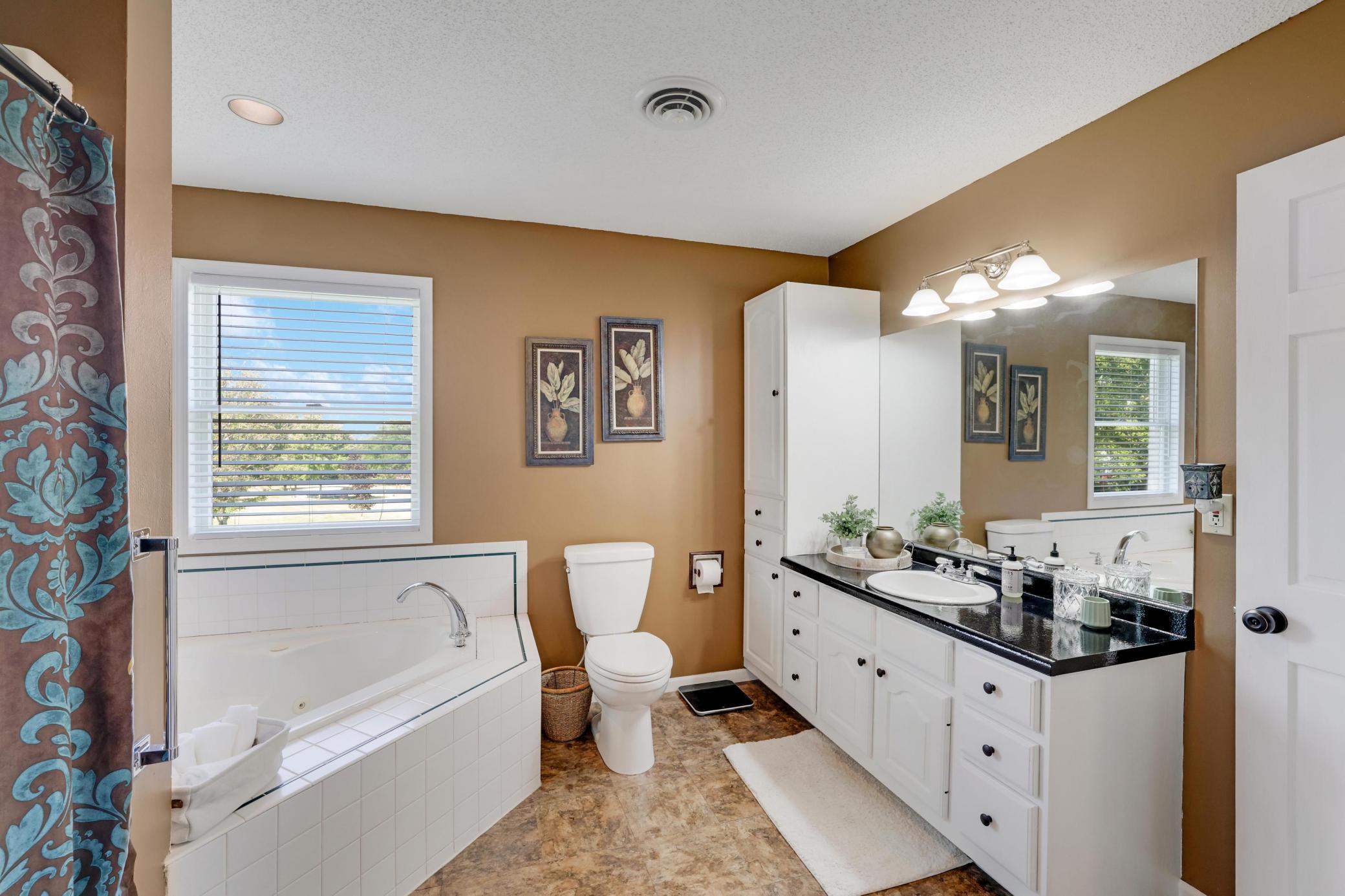 Full walk-thru primary bathroom w/ large soaking tub and shower.