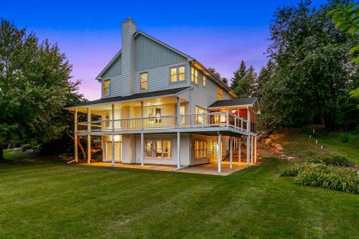 Expansive backyard retreat showcasing the home’s walkout design, wraparound deck and covered patio, all surrounded by mature trees and beautiful landscaping.