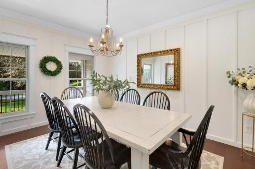 Elegant formal dining room highlighted by custom wall detailing, rich hardwood floors, abundant natural light, and a beautiful statement chandelier.