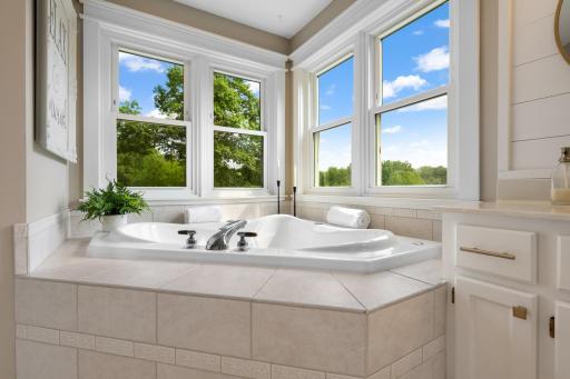 Relaxingsoaking tub surrounded by windows showcasing beautiful treetop and countryside views—your own private retreat.