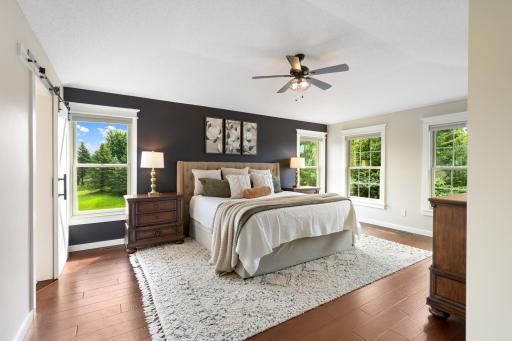 Spacious primary suite featuring rich hardwood floors, abundant natural light, and serene views of the private acreage from every window.