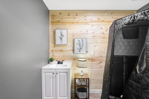 Lower-level sauna room with dedicated vanity and sink—portable sauna shown is not included with the home.