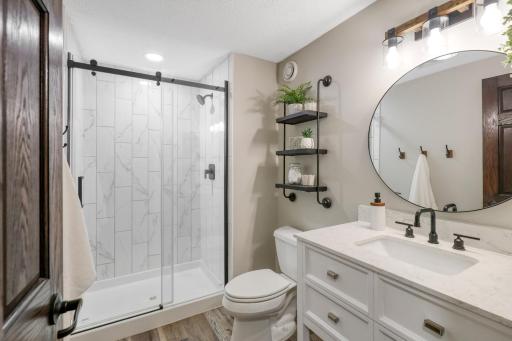 Beautifully updated lower-level 3/4 bath featuring a tiled walk-in shower with glass door, stylish vanity and contemporary finishes.