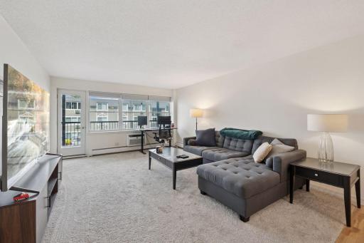 Spacious, sun-filled living room just steps from Lake Bde Maka Ska! This open-concept layout offers oversized windows, private balcony access, and flexible space perfect for a home office or relaxing retreat. Located in a secure building near bike tr