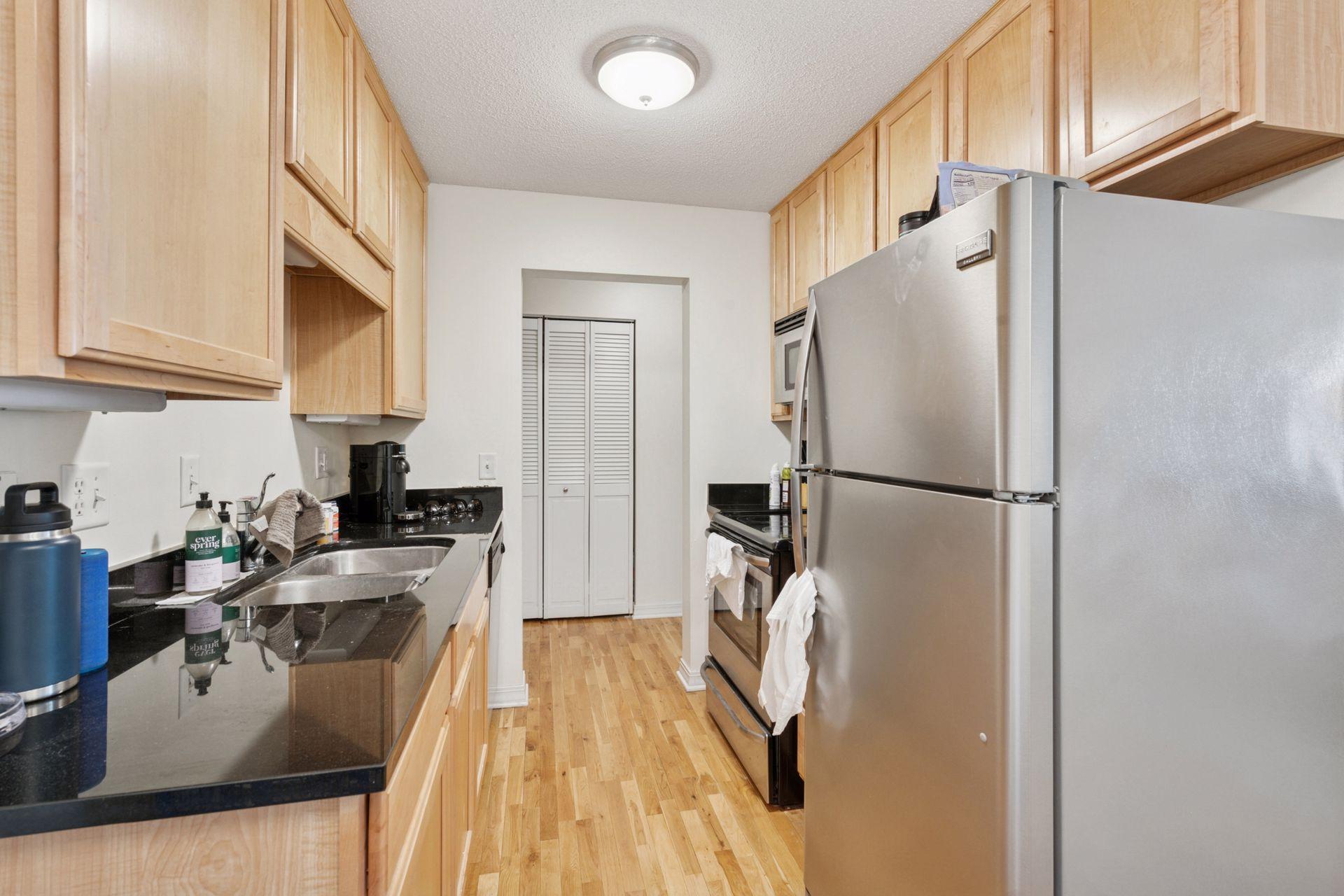 Efficient galley-style kitchen with granite countertops, stainless steel appliances, and hardwood floors—smart design meets modern style just steps from Lake Bde Maka Ska.