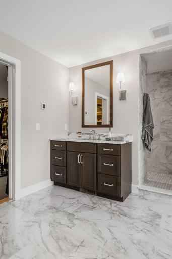 Luxurious Primary Suite w/ auto blinds, spa-like Bath w/ heated floors, freestanding tub, dual vanities & oversized WIC w/ organizational system + pass-through access to Laundry