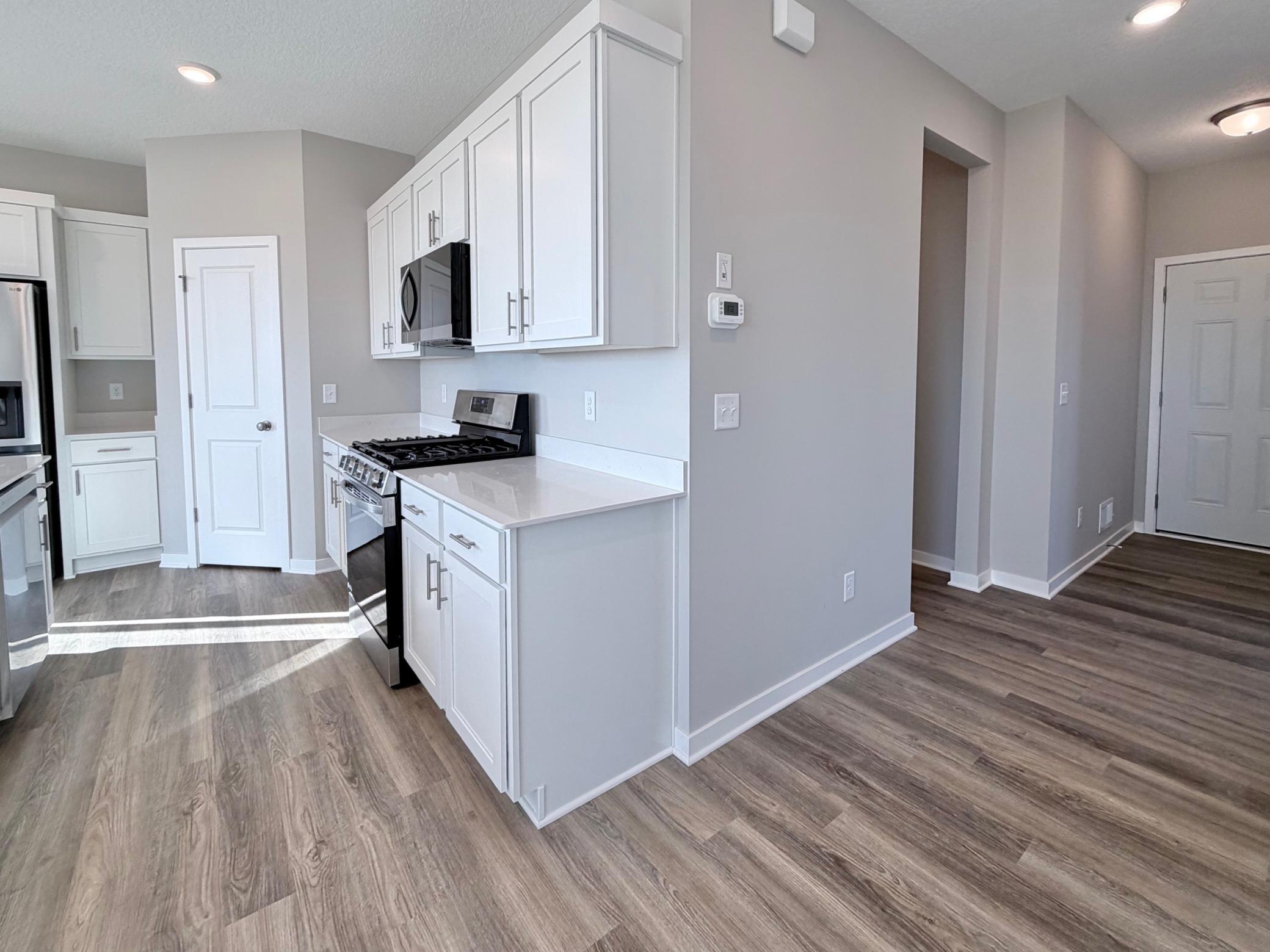 PHOTO OF A DIFFERENT HOME WITH SIMILAR PLAN. FINISHES MAY VARY. Hallway view to Foyer, Mudroom Entrance, and Kitchen.