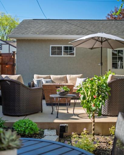 The patio is styled for real living, with generous seating, a shaded table for al fresco dining, and beautiful container gardens that create an outdoor space that rivals any room inside.