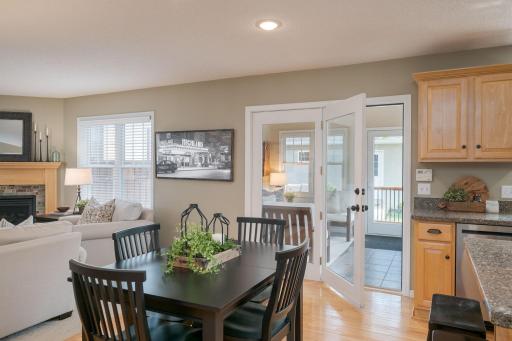 The Eden dining area connects seamlessly to the sunroom beyond. French doors frame the greenery outside while the open layout keeps kitchen, dining, and living all beautifully linked.