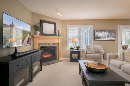 The family room fireplace anchors the space with warmth and character. A stone surround, plastic wood mantle, and glowing fire make this room one everyone gravitates toward.