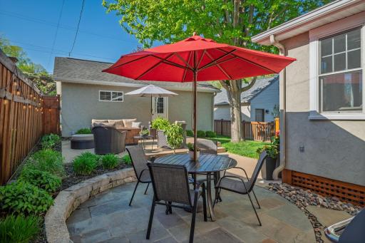 Al Fresco dining at its finest. The shaded patio dining area with a bold red umbrella, stone surround, and lush plantings is the perfect spot for summer lunches and warm evening dinners.