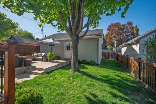 The backyard is a private sanctuary. A lush and manicured lawn, a majestic shade tree deck with patio seating in a beautifully fenced area, create an outdoor retreat that feels worlds away from the city.