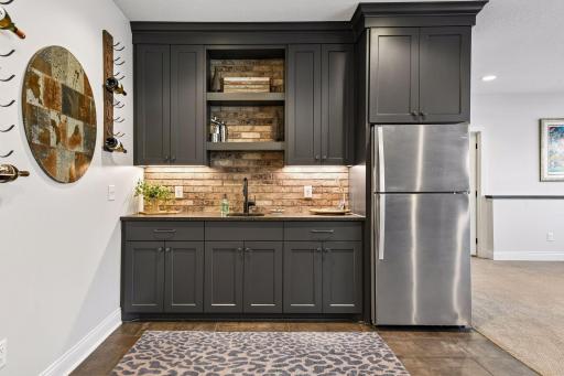 The walk-up wet bar features custom cabinetry and tiled flooring. Just behind the bar is a large, finished storage space that could easily be converted into a future wine cellar.