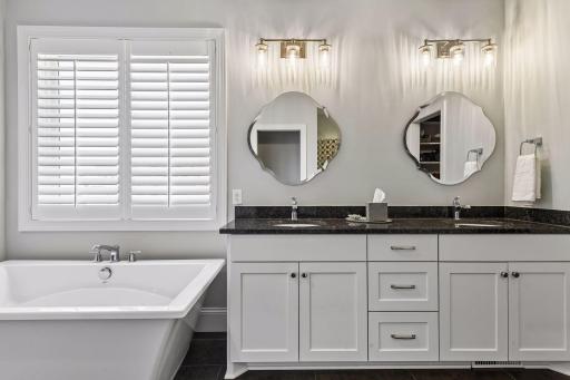 The comfort height vanity features custom cabinetry with granite countertops and designer fixtures from Moen.