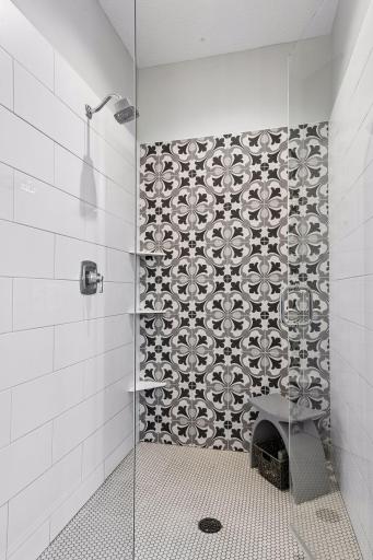 The spacious shower features designer tile and a frameless glass enclosure.