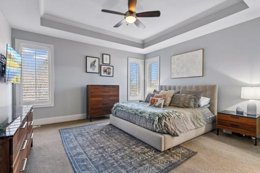 A tranquil retreat, the Primary Suite is a restful space with windows that look out to the backyard and a box vault ceiling with enameled crown molding.