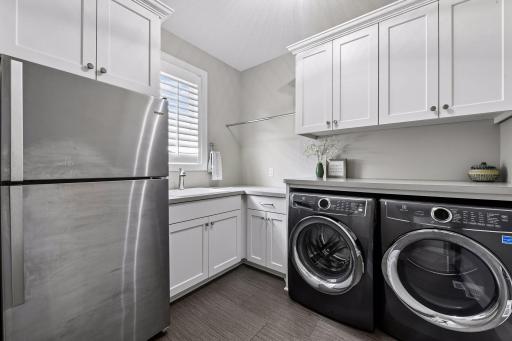 The main level Laundry Room features LVT flooring, custom cabinets and Electrolux steam washer and dryer.