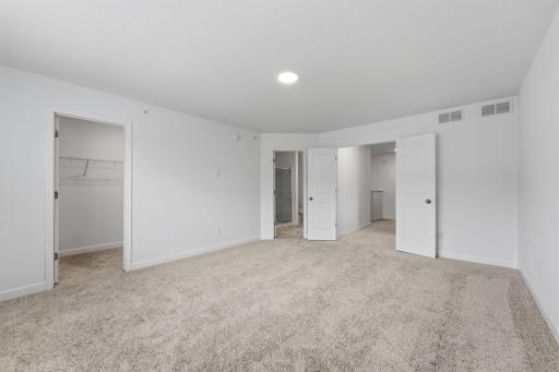 The primary bedroom embraces natural light streaming in from the large windows