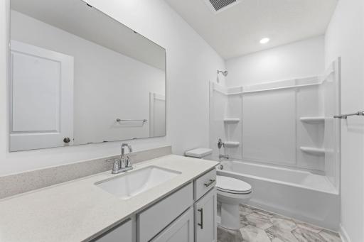 Situated near the secondary bedrooms, this full-sized bathroom comes well-equipped with a quartz-topped vanity and a combination shower and tub to maximize the interior space.