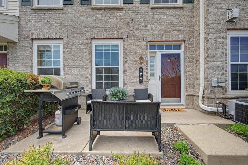 A welcoming front of house photo featuring brick exterior, a red door, and large patio