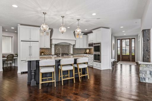 Gourmet kitchen with double ovens, gas cooktop with griddle, beautiful center island w/storage, farmhouse sink, granite counters completed by tile backsplash. Desk station with picture window to view into LL indoor sport court.