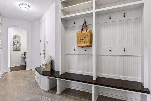 WOW! Look at this drop zone for year-round use for all your needs. Tiled floor, cubbies with hooks and bead board along with walnut stained wood seating area.