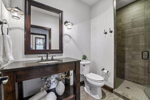 Lower-level bathroom with tile flooring, tile surround shower and custom vanity.