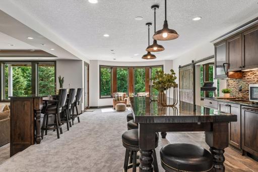 Wet bar area that is not enclosed for ease of flow and seating. To the right is the barn door entrance to workout room and indoor sport court.