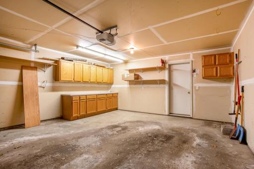 Oversized attached 2-car garage offers abundant storage with built-in cabinetry, shelving, and extra workspace.