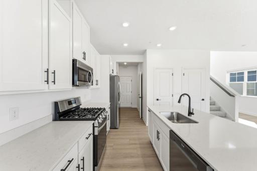 (Photo of a similar home, actual finishes may vary) A subway tile backsplash atop the 5-burner gas cooktop with an overhead microwave meets style with functionality