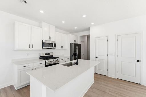 (Photo of a similar home, actual finishes may vary) This chef-ready kitchen is designed to accommodate modern living, with a multiuse center island to add food prep and seating space, gleaming quartz countertops and abundant cabinetry room.