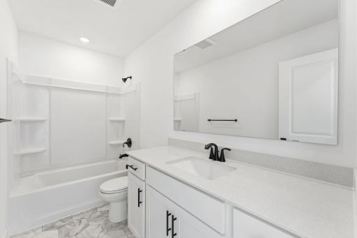 (Photo of a similar home, actual finishes may vary) A full-sized bathroom on the second floor comes well-equipped with a generously sized quartz-topped vanity and a combination shower and tub to maximize the interior space.