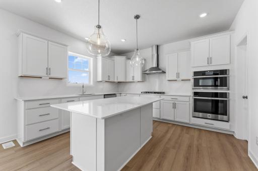 This stylish kitchen showcases a large center island, Shaker-style cabinetry, and brand-new stainless-steel appliances.