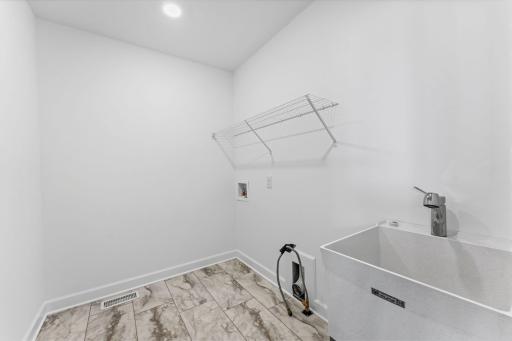 The laundry room will simplify chore days with an overhead shelf and washer-dryer connections.