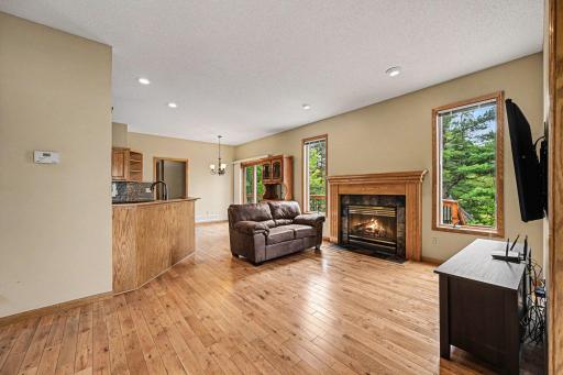Bright, cozy, and open. This perspective showcases the living room's stunning hardwood floors and natural light, anchored by a beautiful gas fireplace with a ceramic tile surroundâideal for chilly evenings.