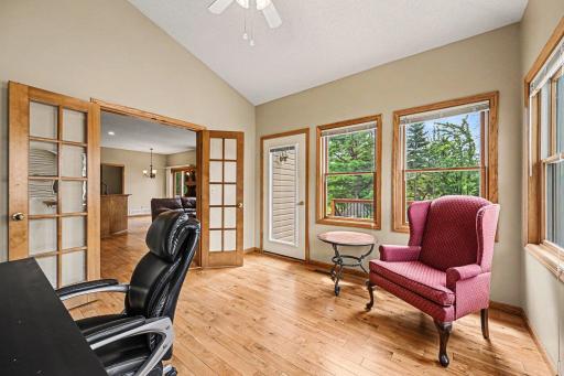 A beautiful sunroom or office off the living room! This bright space features walls of windows, a vaulted ceiling, a lighted ceiling fan, glass French doors, and a separate access door leading straight out to the large backyard deck.